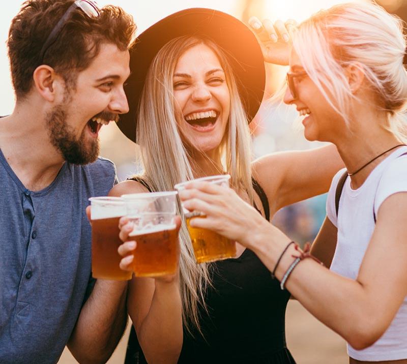Couple of people holding cups full of beer.