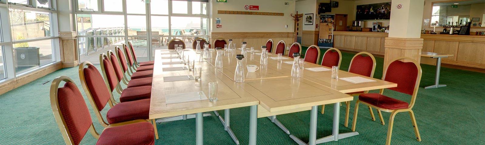 A set of tables joined together in a boardroom style within the Owners and Trainers Suite at Chepstow Racecourse.