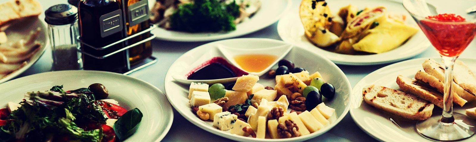 Close up on a table with a number of plates with various food on them.